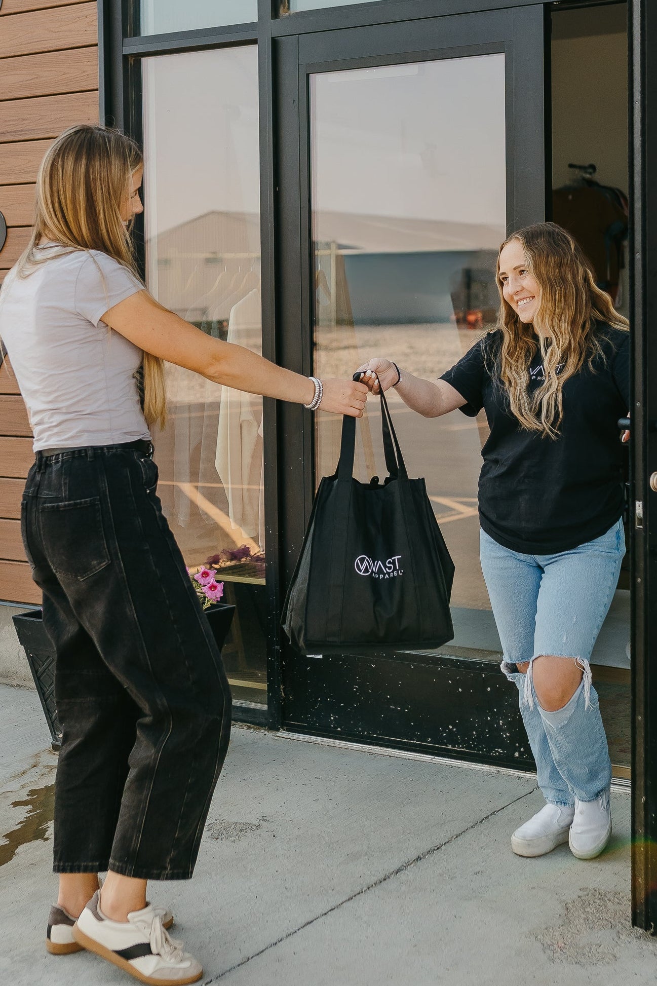 Two women shaking hands outside a building with 'VAST' branding.